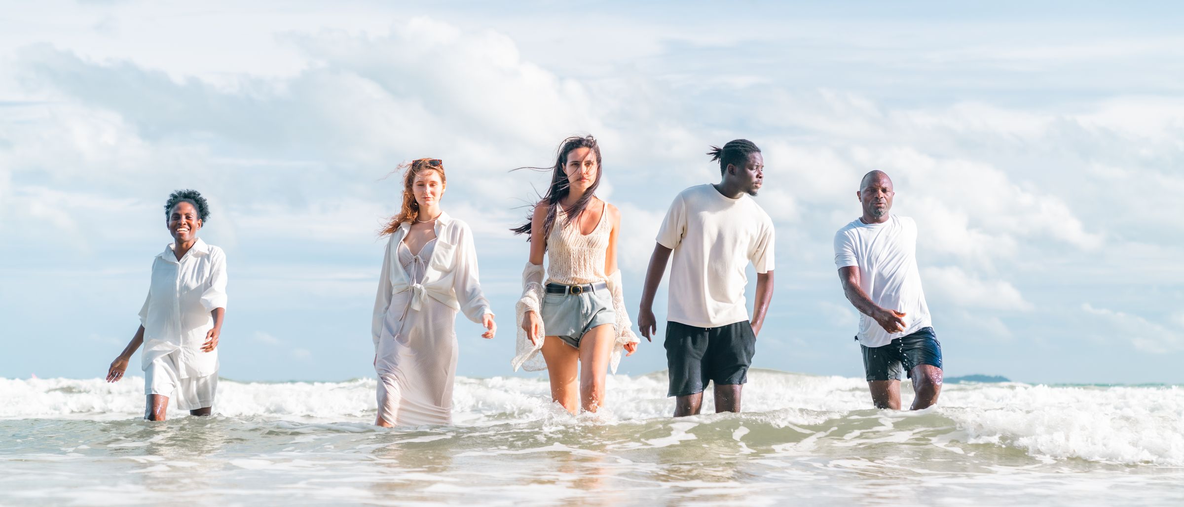 Five friends wading out of the sea on a bright day